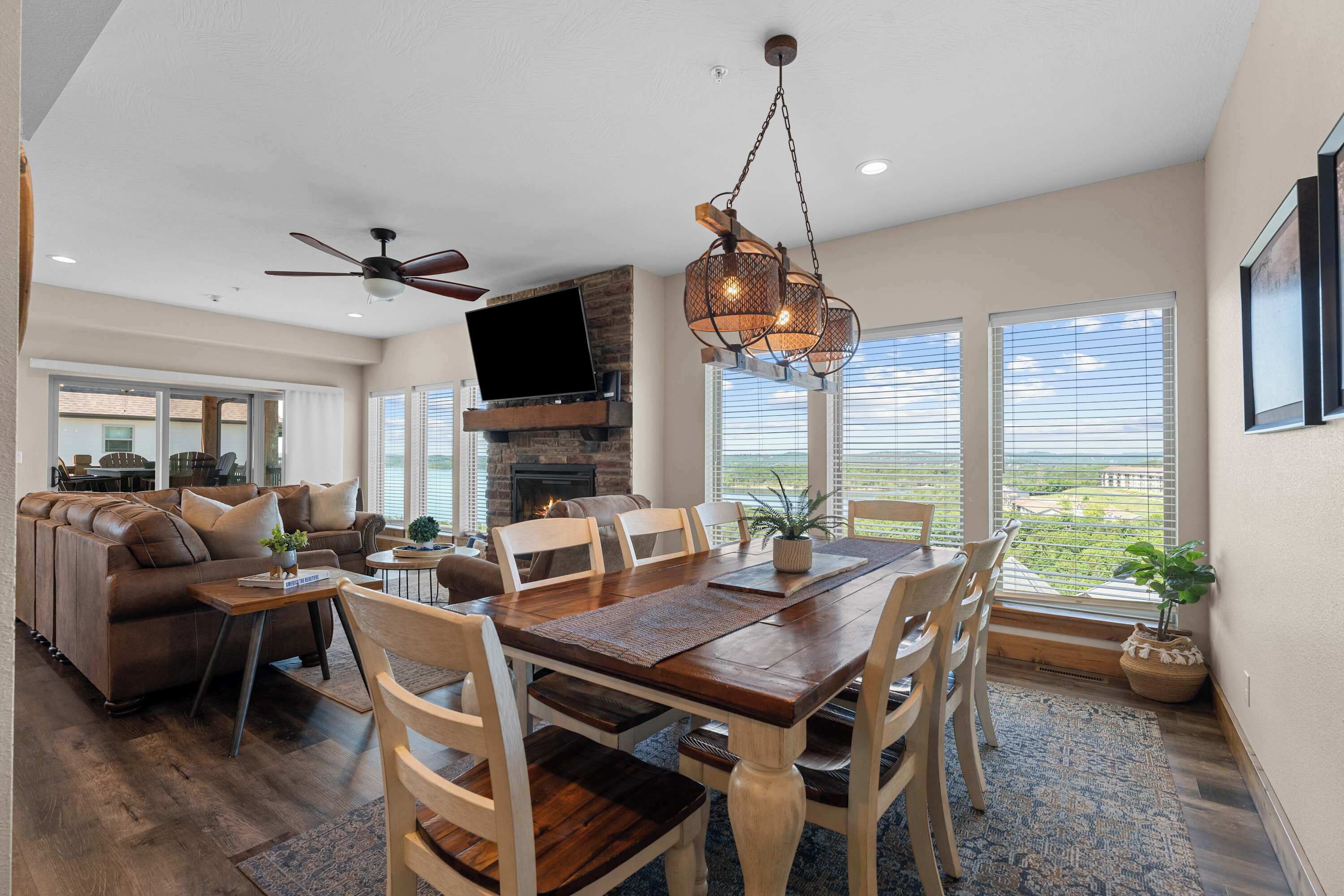 A spacious living area with a fireplace, dining table, and large windows offering a view.