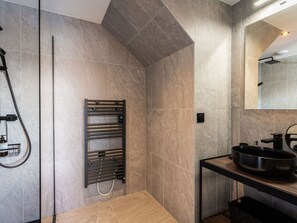 Une salle de bain moderne dotée d’une douche intégrée, d’un porte-serviettes et d’un lavabo avec un grand bac.