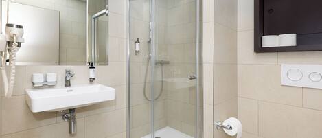 A modern bathroom with a glass-enclosed shower, a white sink, and a toilet.