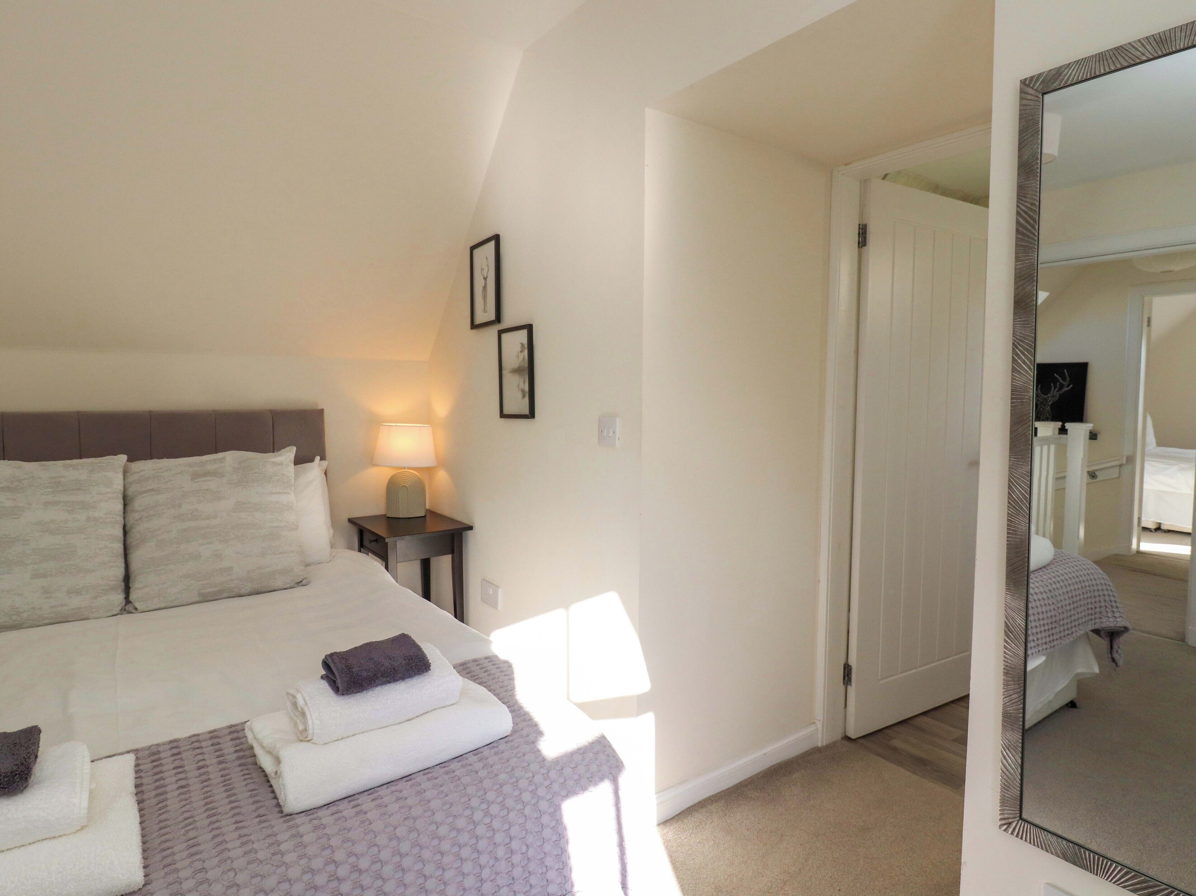 A bedroom with a bed, bedside lamp, and a mirror.