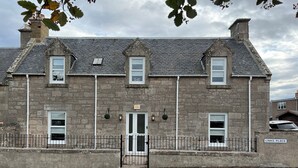 A stone building with a traditional design, featuring a central door, multiple windows, and a sign reading "LINKS PLACE". - 1 Links Place (Nairn)