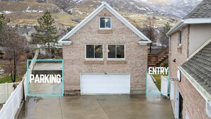 A two-story house with a garage, surrounded by a mountainous landscape. - Lone Peak View | Pickleball + Putting Green (Draper)