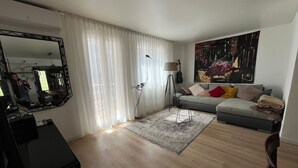 A modern living room with a grey sofa, a large mirror, and a floor lamp.