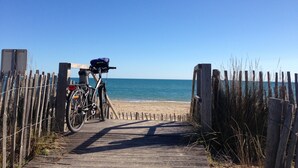 A wooden pathway leading to a beach with a bicycle parked on the left.