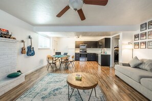 Un salon moderne doté d’une cheminée, d’un coin repas, d’une cuisine et d’un ventilateur de plafond.
