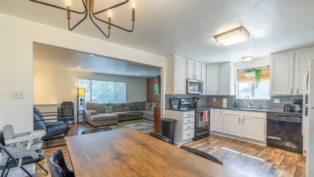 A modern kitchen with white cabinets, a microwave, and a black stove.