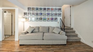 A living room with a sofa, framed pictures on the wall, and a staircase.