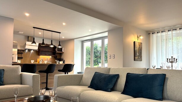 A modern living room with a sofa, a coffee table, and a kitchen area in the background. - Authentic cottage in Auvergne, 8 pers, pets allowed (Autry-Issards)