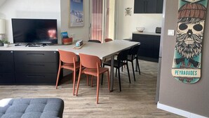 A modern kitchen with a dining area, featuring a TV, a large island, and a wall-mounted artwork.