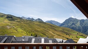 A view of a mountain landscape with a wooden balcony overlooking a valley.