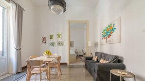 A modern living room with a dining area, a gray sofa, and a small table with a lamp. - Casa Markea by Wonderful Italy (Palermo)