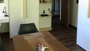 A dining area with a wooden table, a chair, and a cabinet with shelves.