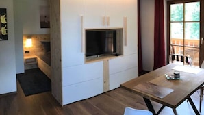A modern kitchen with a built-in TV, wooden cabinets, and a dining area with a table and chairs.