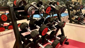 Ein Fitnessraum mit einer Hantelbank und einer roten Matte auf dem Boden.