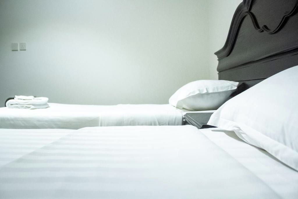 Quarto de hotel com duas camas, roupa de cama branca e uma cama arrumada à esquerda.