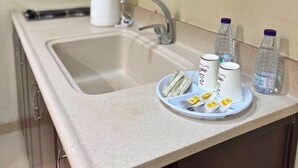 Eine Küche mit Spüle, Wasserkocher und einem Teller mit Tassen und Flaschen.