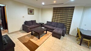 Ein Wohnzimmer mit zwei Sofas, einem Couchtisch, einem Fernseher und einem Esstisch mit Stühlen.