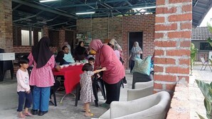 An indoor event with a brick wall, a red table, and people gathered around. - Desa Retreat Kuala Kangsar (Kuala Kangsar)