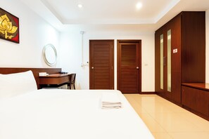 Una habitación de hotel con cama, escritorio, armario y espejo.