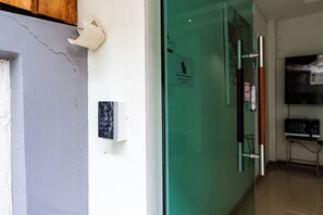 A hallway with a door, a wall-mounted intercom, and a green door with a sign. - Yon INN Sukhumvit 4 - BTS Nana (Bangkok)