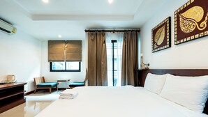 Habitación de hotel con una cama grande, un escritorio, una silla y un ventanal con cortinas.