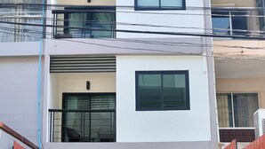 A modern two-story building with a balcony, a small outdoor seating area, and a gated entrance. - Yon INN Sukhumvit 4 - BTS Nana (Bangkok)