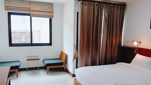 A hotel room with a bed, a desk with a chair, a small table, and a window with blinds. - Yon INN Sukhumvit 4 - BTS Nana (Bangkok)