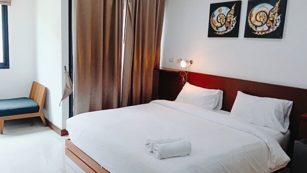 A hotel room with a bed, a chair, and two wall-mounted artworks. - Yon INN Sukhumvit 4 - BTS Nana (Bangkok)