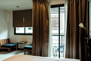 Habitación de hotel con cama, una mesita, una silla y un balcón con vistas.