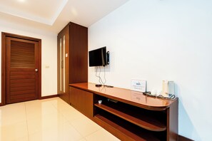 Zona de recepción de un hotel con un mostrador de madera, un televisor de pantalla plana en la pared, un cartel de WiFi y una máquina de café.
