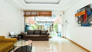 Una sala de estar moderna con un sofá, una mesa de centro de vidrio y un sillón amarillo.