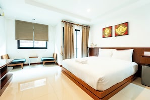A hotel room with a large bed, a desk, two chairs, a small table, and two paintings on the wall. - Yon INN Sukhumvit 4 - BTS Nana (Bangkok)