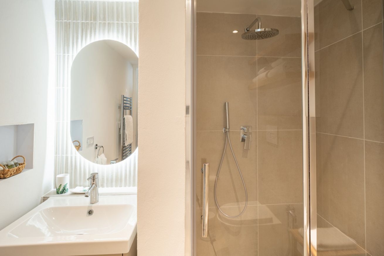 A modern bathroom with a sink, mirror, and shower.
