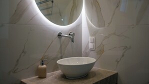 A bathroom with a marble sink, a soap dispenser, and a mirror. - Corfelia Seaview Suites (Corfu)