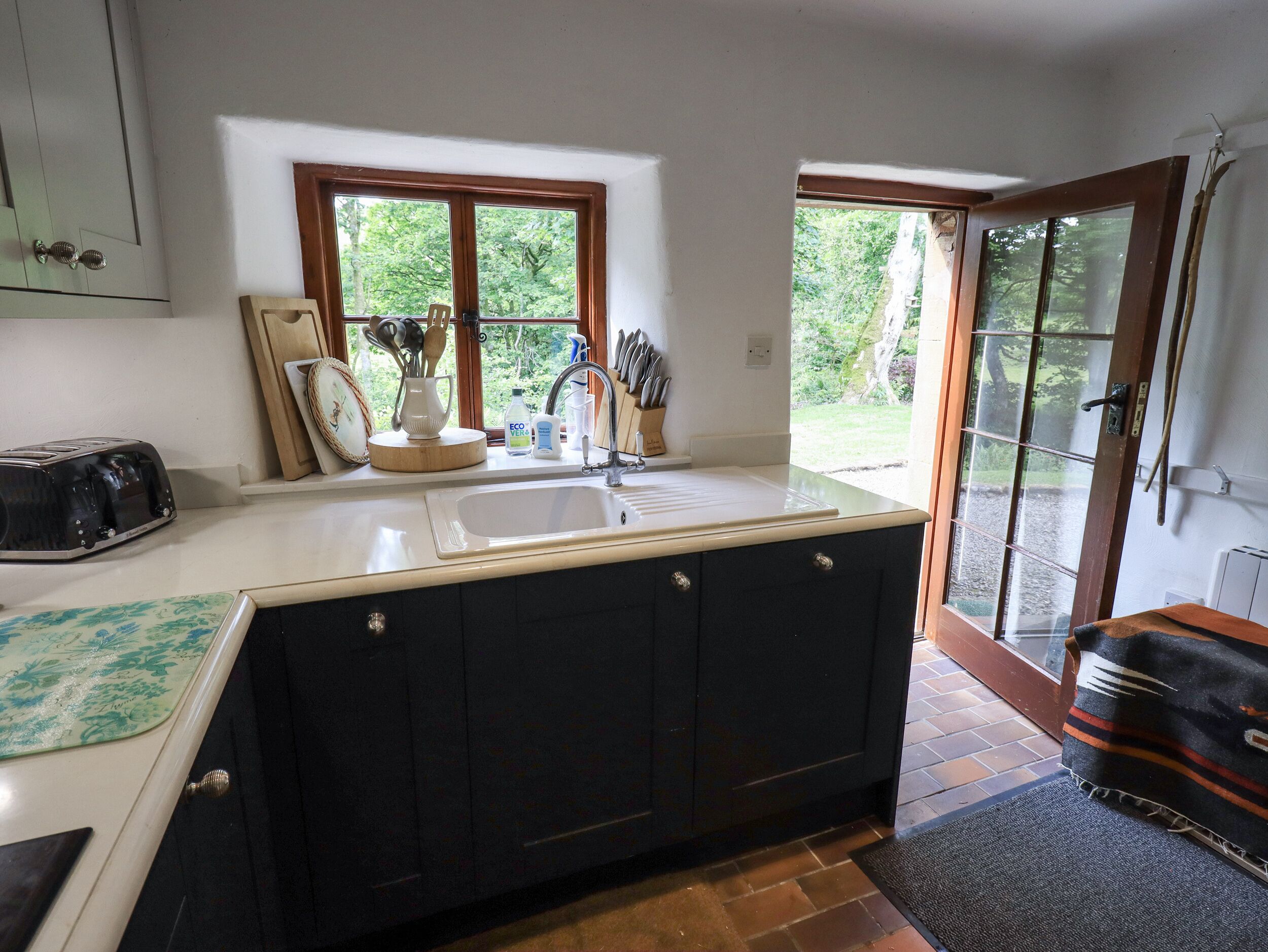 A kitchen with a large island, a sink, and a window overlooking a garden.