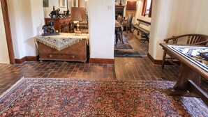 A traditional room with a wooden dresser, a patterned rug, and a dining area with a bench and table. - Chapel Cottage (Cleator)