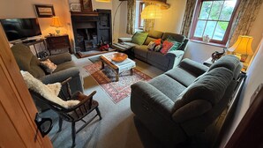 A cozy living room with a fireplace, comfortable seating, and a television. - Chapel Cottage (Cleator)