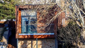 Uma casa moderna de dois andares com fachada de tijolos e grandes janelas.