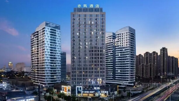 Un hotel de gran altura con varios pisos, rodeado de otros edificios altos y una calle concurrida con vehículos en movimiento.