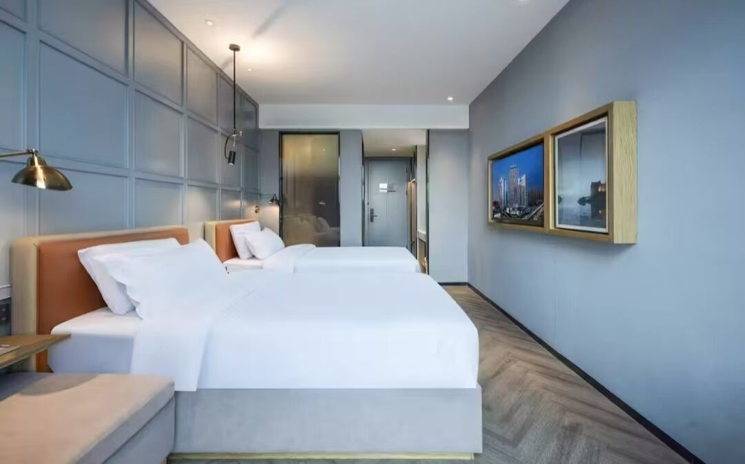Una habitación de hotel moderna con una cama grande, mesitas de noche y un cuadro enmarcado en la pared.