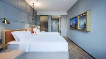 Una habitación de hotel moderna con una cama grande, mesitas de noche y un cuadro enmarcado en la pared.