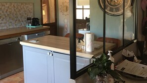 A kitchen with a large island, a clock, and a window with a view of the outside.
