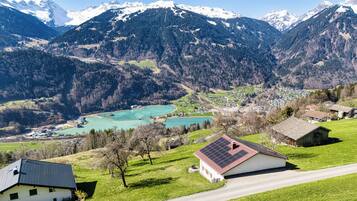 Ländliche Landschaft mit einem kleinen Haus, das ein Solardach hat, umgeben von grünen Feldern und einer Straße.