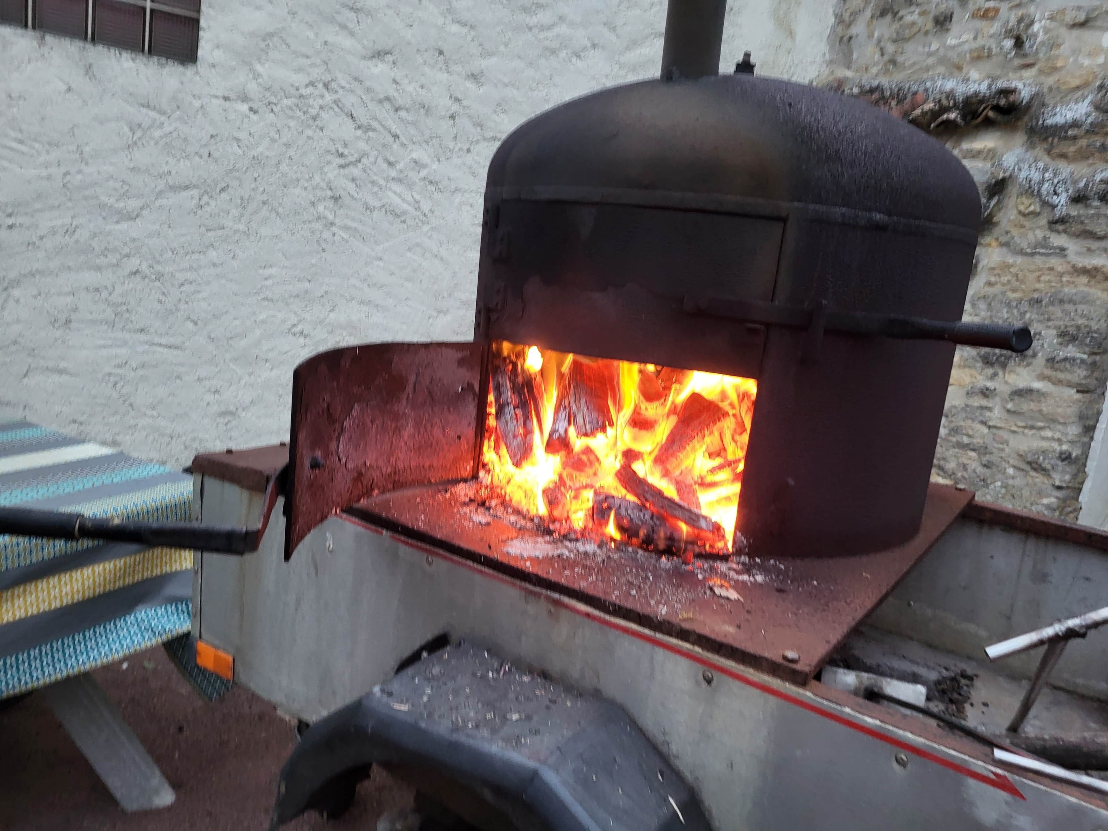 En brændeovn med synlige flammer, monteret på en trailer.