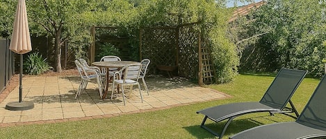 An outdoor patio with a table and chairs, a lounge chair, and a soccer ball.