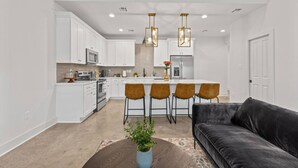 A modern kitchen with white cabinets, a central island with bar stools, and pendant lighting. - NEW•Voodoo House•KING Bed• (Lafayette)