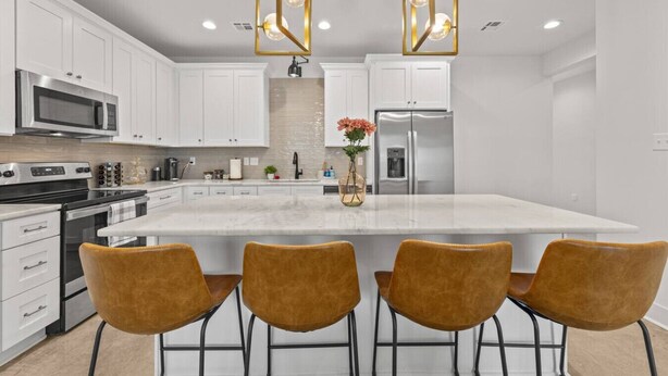 A modern kitchen with white cabinets, a large island, and four bar stools. - NEW•Voodoo House•KING Bed• (Lafayette)