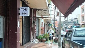 Une rue étroite avec une enseigne indiquant « Toss Inn » et un homme qui marche.