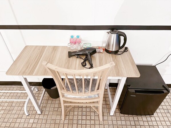 A small wooden table with a kettle, a hairdryer, and some toiletries. - Toss Inn Hat Yai (Hat Yai)