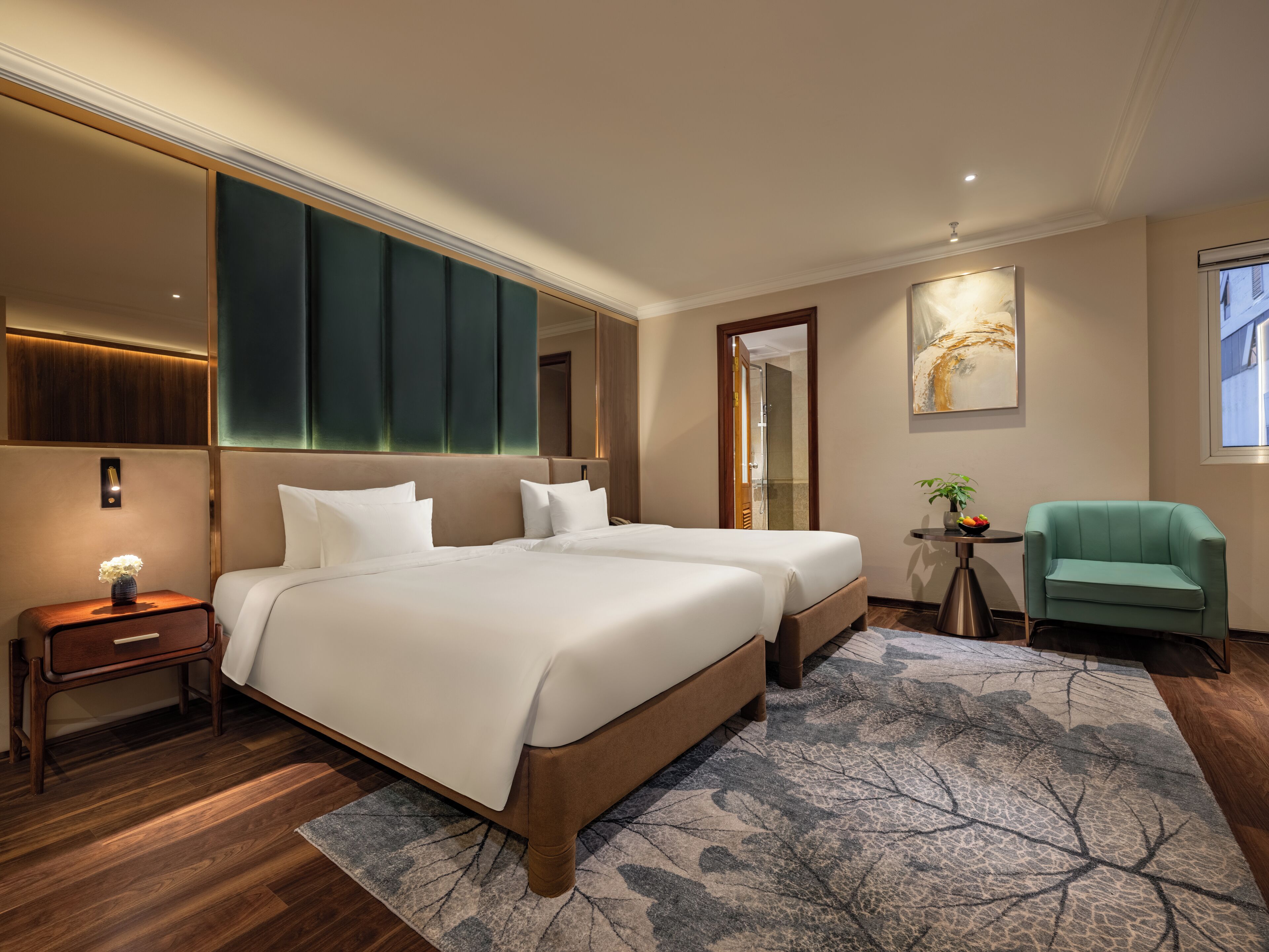 A hotel room with two beds, a small side table, a chair, a mirror, and a painting on the wall.